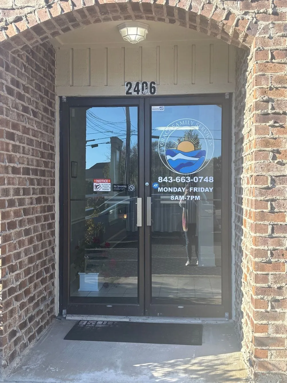 Front entrance of Grace Family Services with the logo and phone number on the glass door