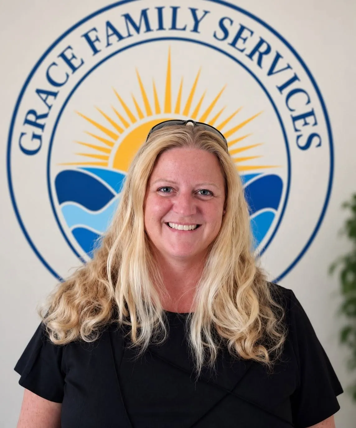 Nikki, therapist, smiling in front of the Grace Family Services logo mural